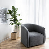 The Evita Swivel Chair in slate grey boucle. Its low profile makes it ideal for placement in a bedroom corner, a cozy reading nook, or as the perfect complement to your living room seating. Crafted in Europe and upholstered in a luxe boucle fabric, this barrel chair not only exudes sophistication but also boasts a hidden swivel base, allowing for subtle rotations around the room. Experience both style and functionality with this chic swivel chair designed to elevate the ambiance of any space in your home.